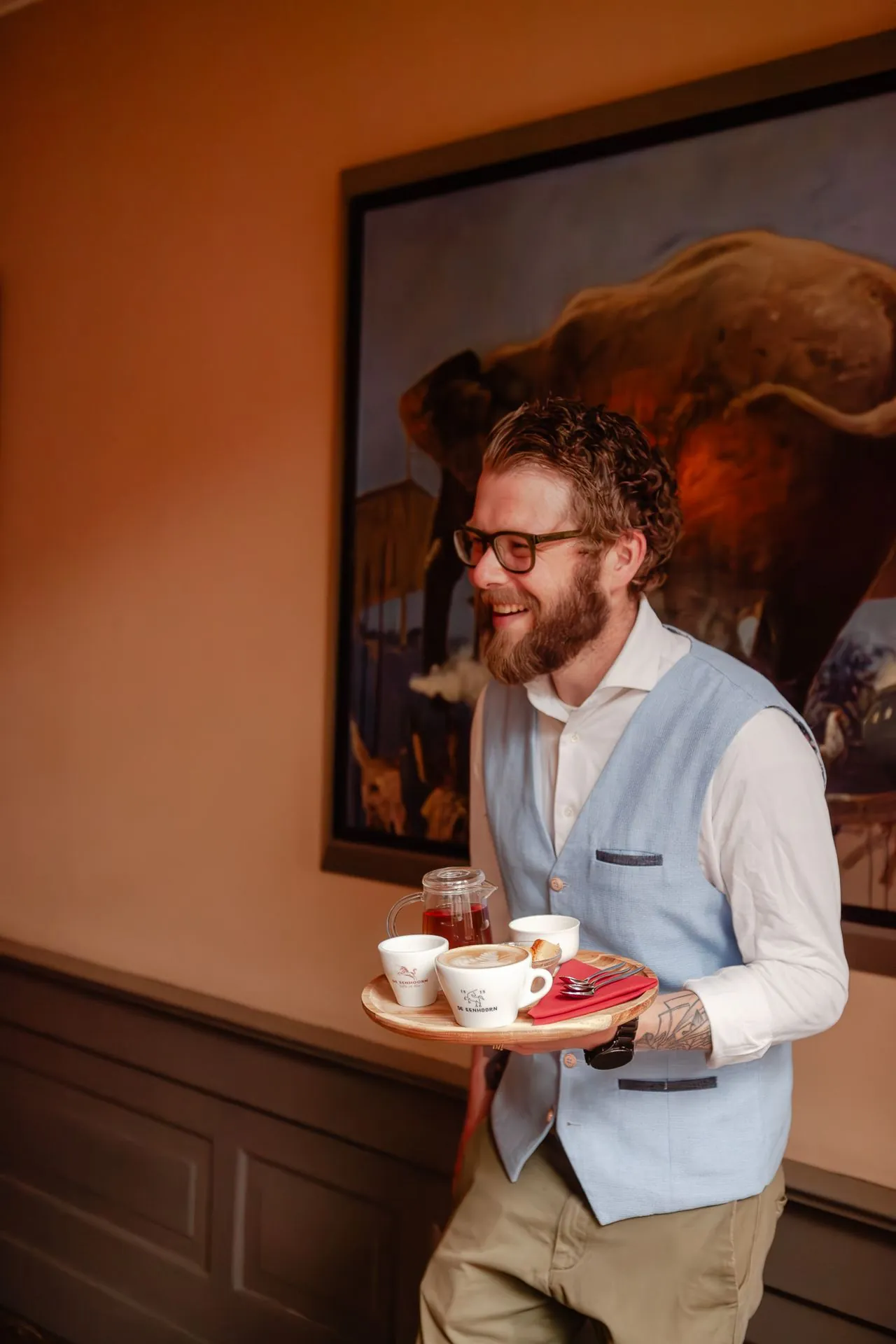 Medewerker van De Eenhoorn serveert koffie op een dienblad